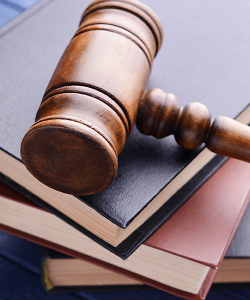 A wooden judge’s gavel resting on a stack of thick legal law books
