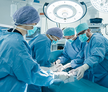 A surgical team of four performing an operation under bright lights in a modern hospital operating room